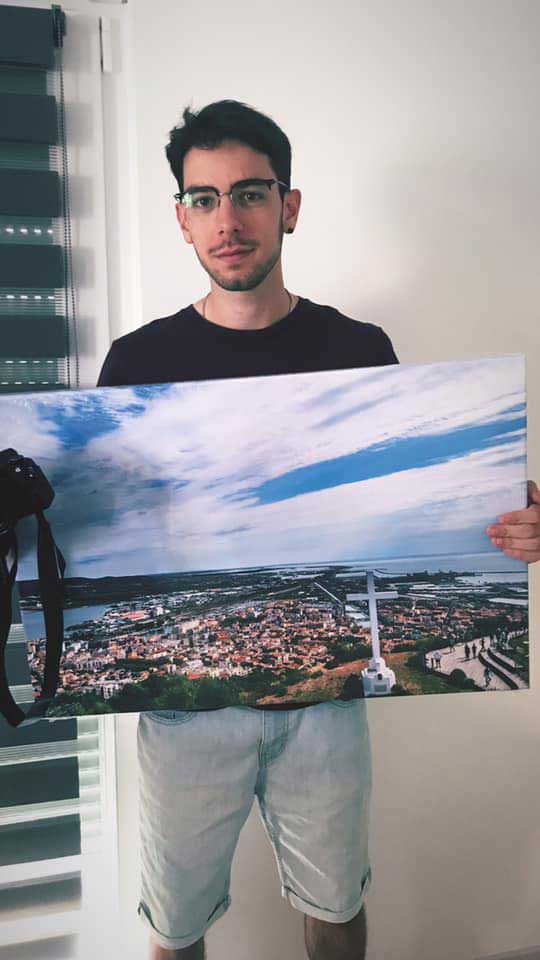 Quentin Mores devant une de ses photographies à vendre sur toile.